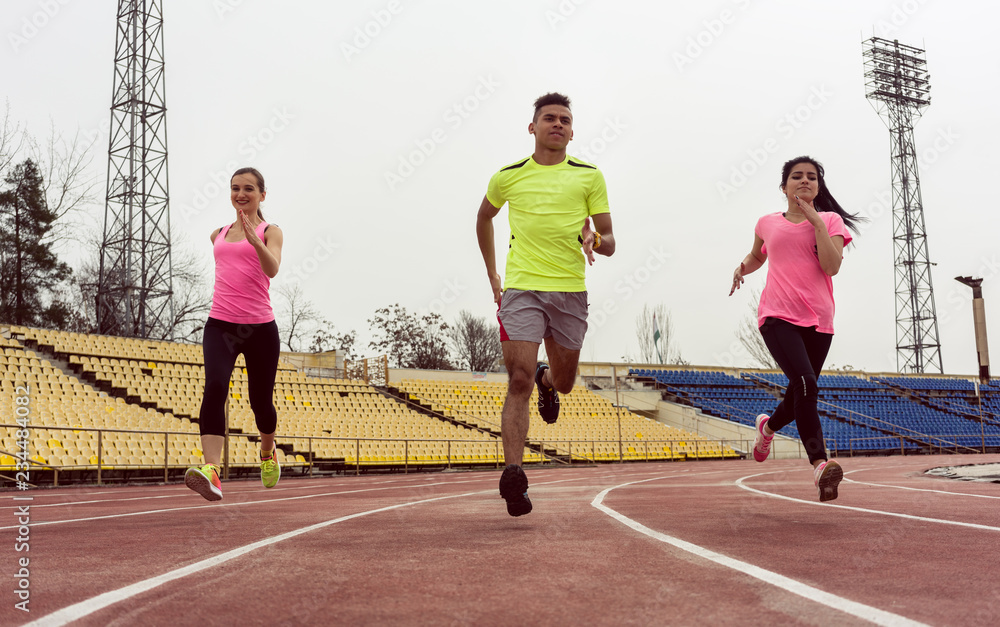Obraz premium Young caucasian friends doing running practice on ground