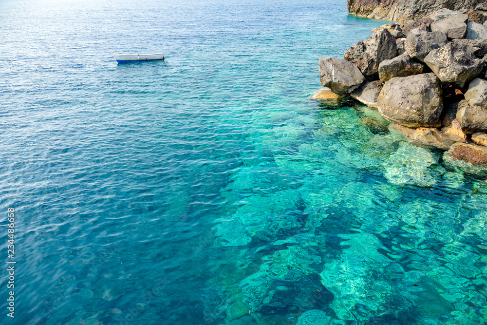 Blue clear water and rocks of island Santorini, Greece