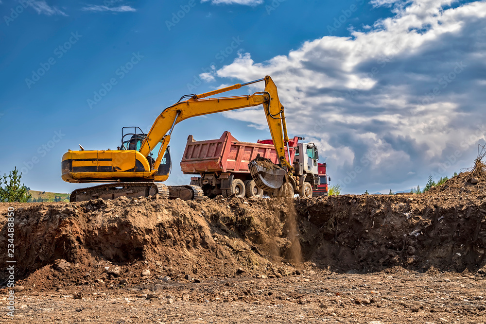 Yellow excavator and empty truck working at the construction site Yellow excavator and empty truck working at the construction site