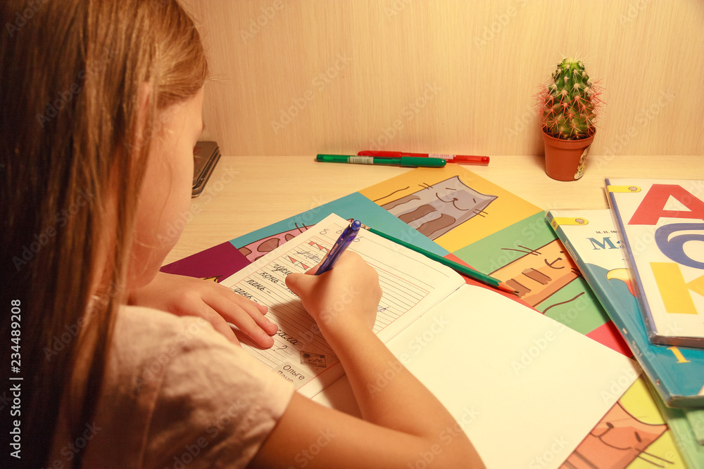 girl holding a pencil and writing in a notebook words and letters