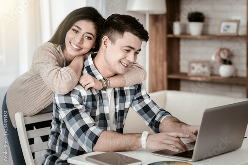 Loving couple. Delighted male person expressing positivity while working at home