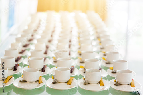 A lot of white coffee cups and brown sugar in the seminar with blurred background.