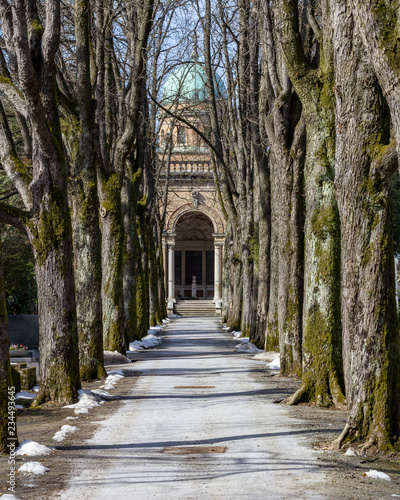Winter scene in Mirogoj Cemetery in Zagreb, Croatia where a tree lined path leads to the domed entrance