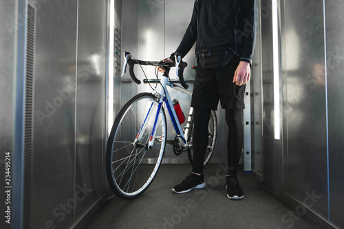 Close-up photo of cyclist's foot and highway bike in the elevator. Cyclist lives in a high-rise building that bikes an elevator. Copyspace