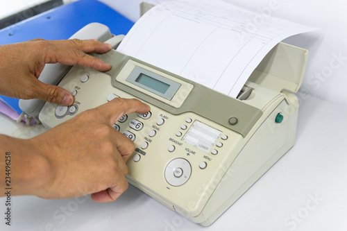 Hand man are using a fax machine send paper in the office Business concept 