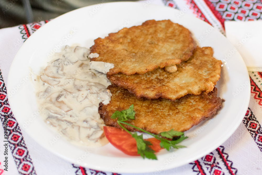 Potato pancakes with mushroom sauce on a white plate.