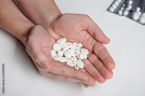 Handful of pills in men palms on white background