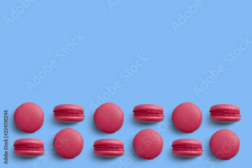Macaroons on colored background, a pattern of colorful french cookies macarons. Beige, brown french cookies macarons on red background. Gift for Valentine's Day