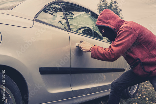 Bild auf Leinwand Side view of car being forced by a man in hoodie and mask