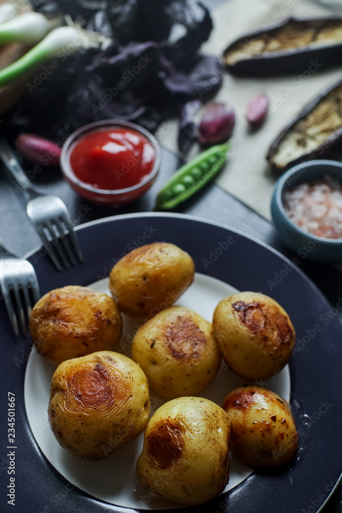 Delicious dinner table for two with fried potatoes, organic tomatoes salad, olives, green onion, eggplants, eggs on dark stone background. Delicious dinner table for two with fried potatoes, organic tomatoes salad, olives, green onion, eggplants, eggs on dark stone background.
