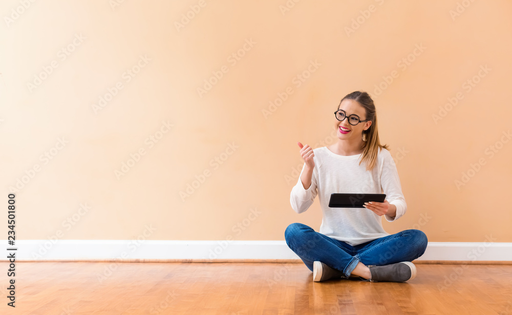 Young woman with a tablet computer against a big interior wall