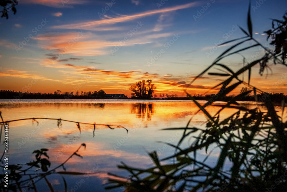Sunset above lake in polder landscape with reflection in the water Sunset above lake in polder landscape with reflection in the water