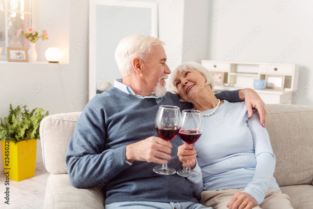 Mature couple looking at each other with tenderness while drinking red wine at home Mature couple looking at each other with tenderness while drinking red wine at home