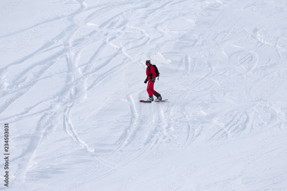 Snowboarder downhill on snowy ski slope