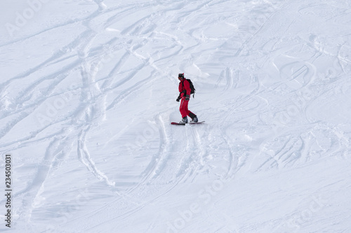 Snowboarder downhill on snowy ski slope