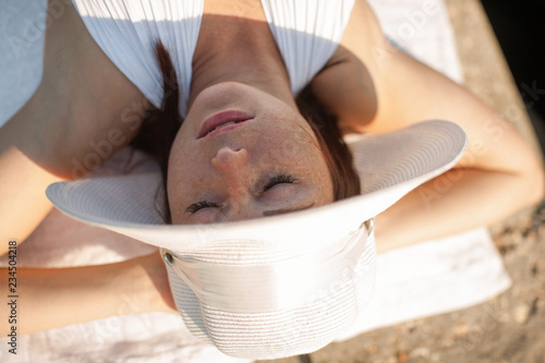 Girl sunbathing with hands behind head and eyes closed