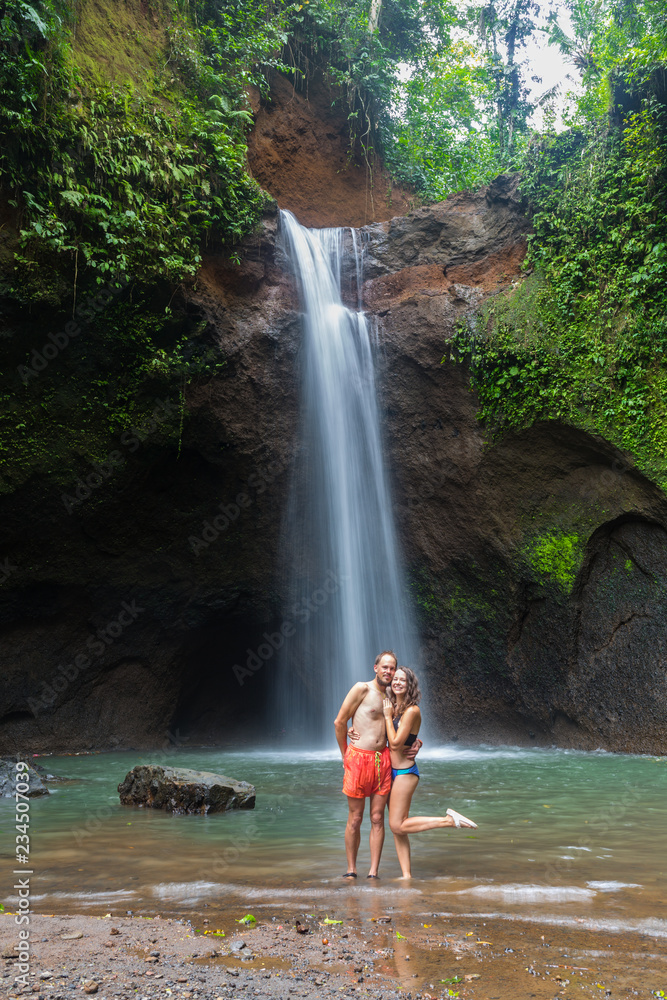 couple looking at the gorgeous waterfall in Bali couple looking at the gorgeous waterfall in Bali