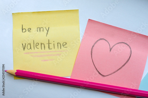 Be My Valentine handwritten inscription on the yellow sticker and the heart drawn on a pink paper with pencil. Homemade greeting cards for Saint Valentine's Day