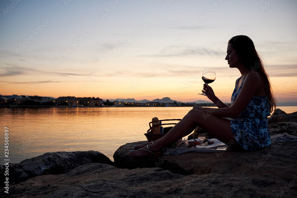 Young girl drinking wine on the beach