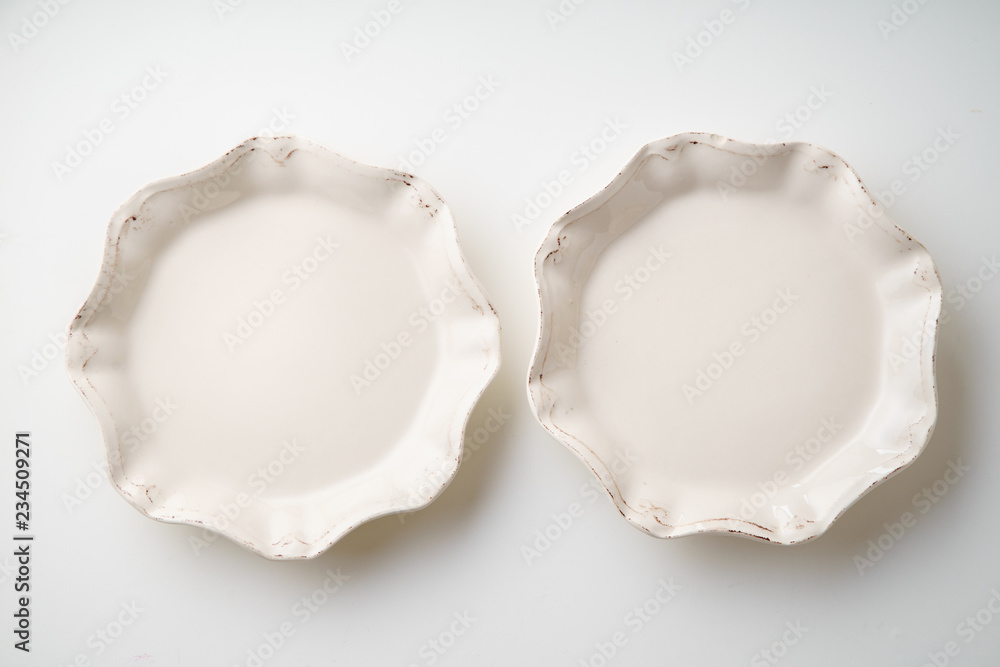 Porcelain plates of various form and size on white background. Overhead image, copy space. Porcelain plates of various form and size on white background. Overhead image, copy space.
