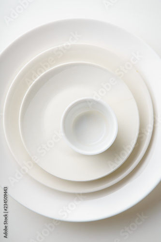 Porcelain plates of various form and size on white background. Overhead image  copy space.