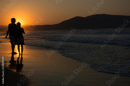Couple in love walking on Sea sunset. Sunny path at dusk and hills on background. Georgioupolis beach, Crete Greece