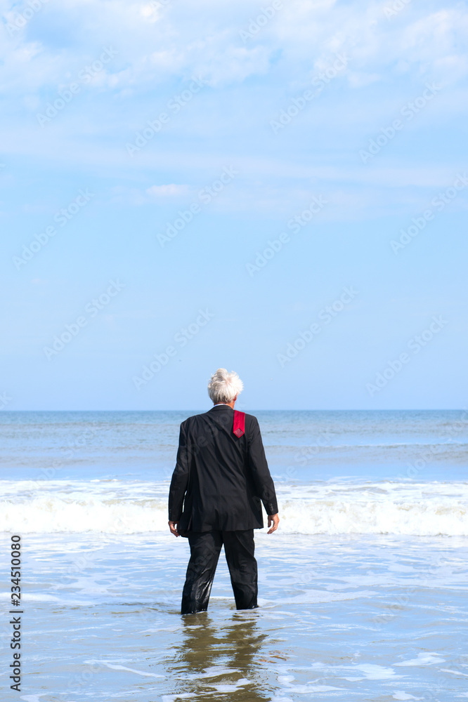 Business man walking into the beach Business man walking into the beach