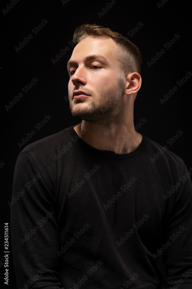 Closeup portrait of a stylish young man with a stubble on his face wearing a black jacket. Fashionable, advertising and commercial design.