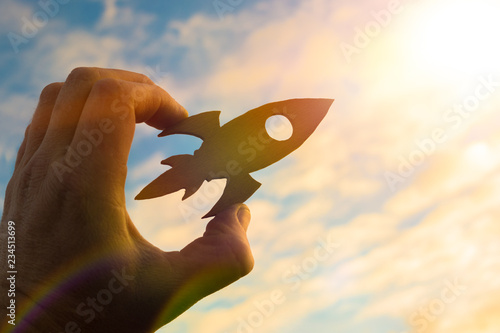 Start up concept. Rocket in the hand of a businessman against the sky in the rays of the sun. Business idea, creative. success and achievement, career growth.