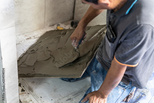 Construction Laborer or industrial tiler builder worker installing floor tile at home. renovate concept.