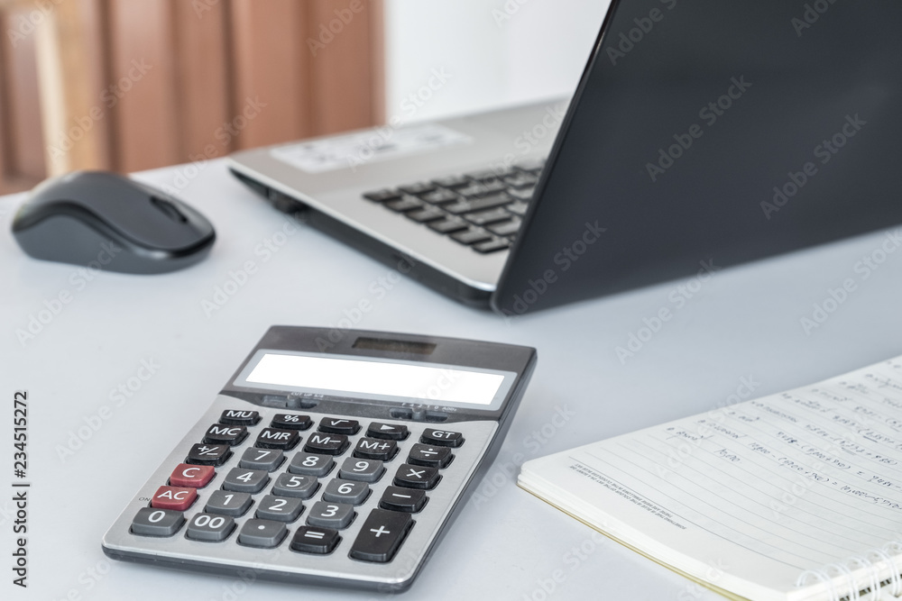 Calculator, laptop computer mouse, placed on a white desk. Calculator, laptop computer mouse, placed on a white desk.