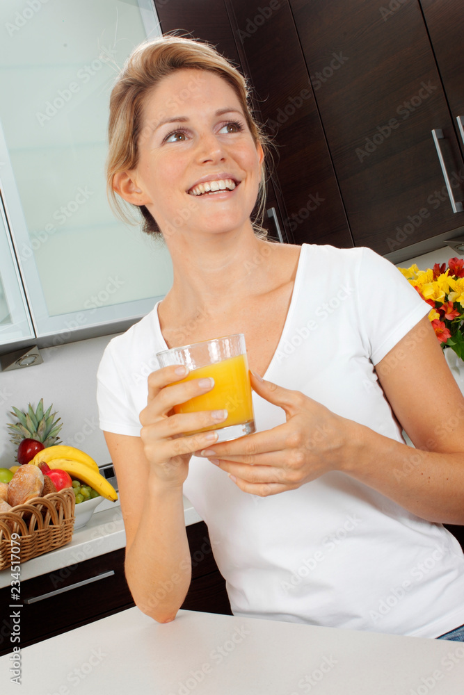 WOMAN IN KITCHEN DRINKING GLASS OF ORANGE JUICE WOMAN IN KITCHEN DRINKING GLASS OF ORANGE JUICE