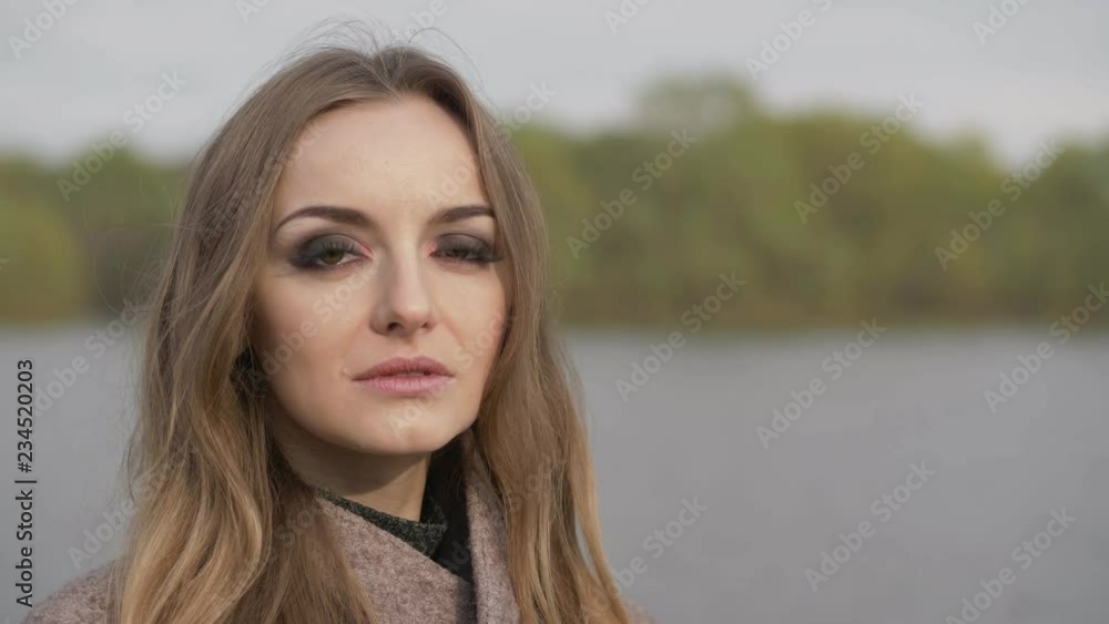 Beautiful fashionable blonde woman with gorgeous makeup in blush jacket pensive looking aside, into camera. Close up slow motion portrait Beautiful fashionable blonde woman with gorgeous makeup in blush jacket pensive looking aside, into camera. Close up slow motion portrait