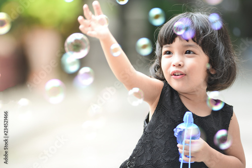 Asian little cute girl or kid blow,play air soap bubbles with smile. happiness,fun and childhood concept.
