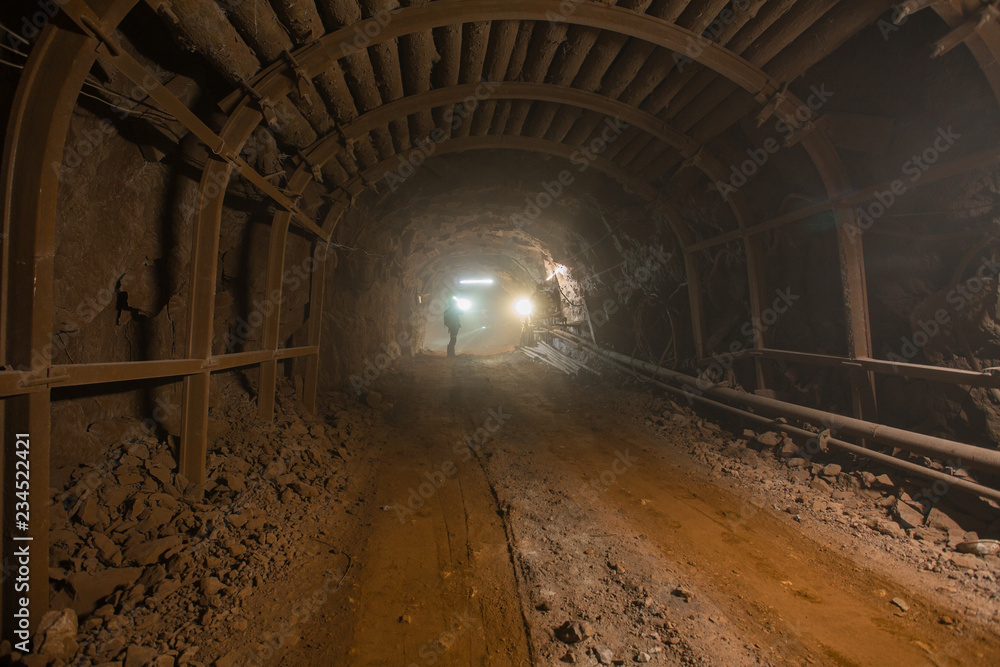 Underground gold iron ore mine shaft tunnel gallery passage with light and timbering