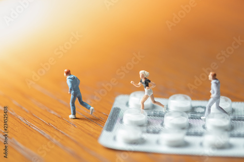 Sport  medicine and health care concept. Group of man and woman miniature figure running on pills or tablets in blister packs.