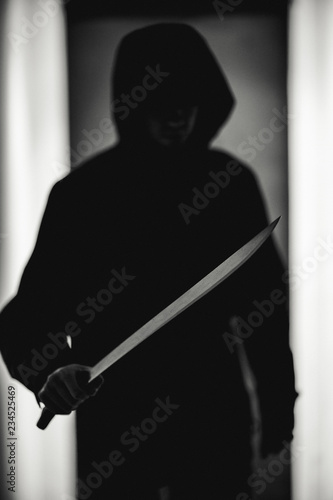 Black and white photo of criminal in hood with machete
