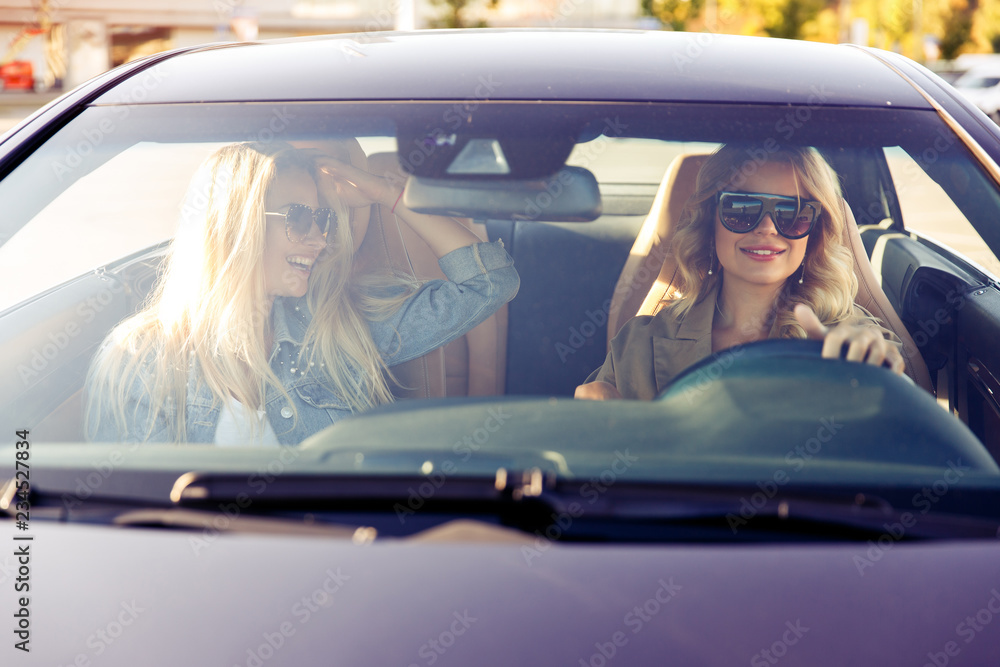 Photo through windshield of blondes wearing sunglasses while