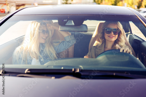 Photo through windshield of blondes wearing sunglasses while driving in car photo