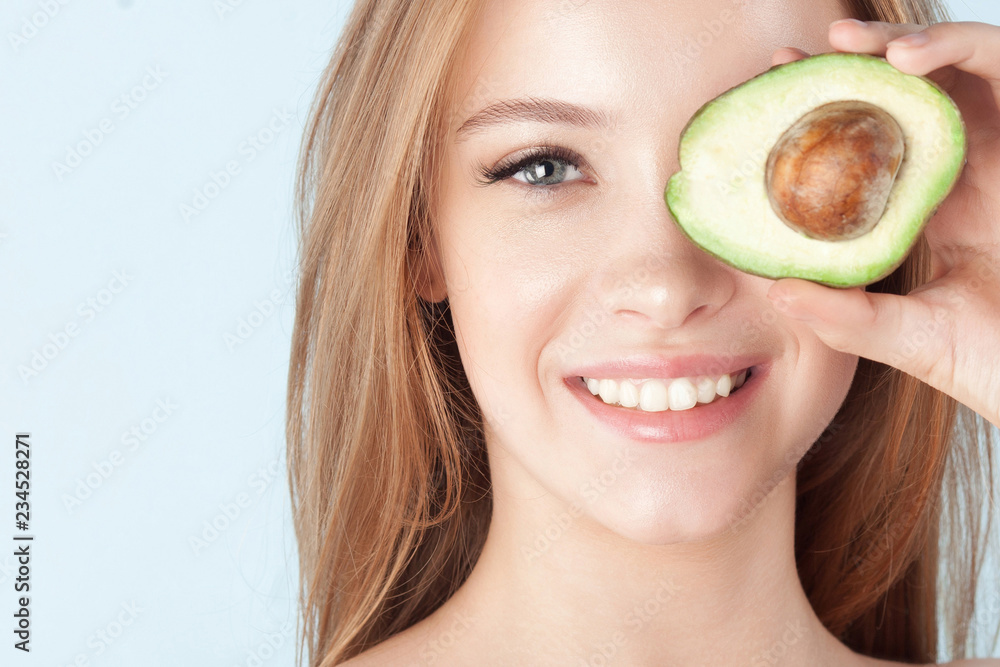 Young beautiful girl smiling with avocado close-up Young beautiful girl smiling with avocado close-up