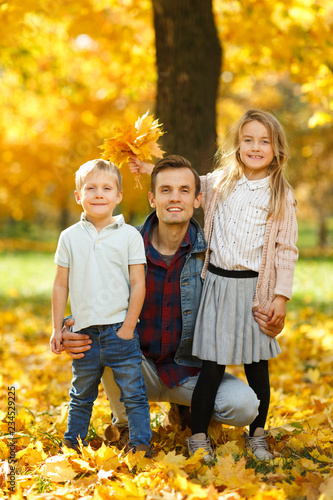 Image of young father with daughter and son in autumn park walking