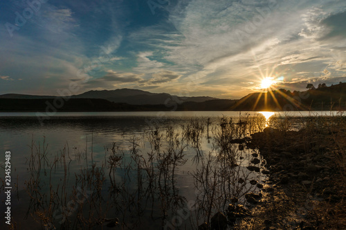 Landscape of unset reflected in the lake with sunbeams