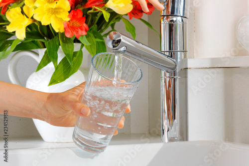 WOMAN POURING GLASS OF TAP WATER photo