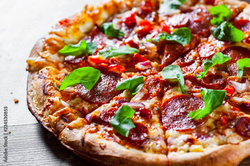 sliced Pepperoni Pizza with Mozzarella cheese, salami, chorizo, tomato sauce, pepper, Spices and Fresh arugula. Italian pizza on wooden table background sliced Pepperoni Pizza with Mozzarella cheese, salami, chorizo, tomato sauce, pepper, Spices and Fresh arugula. Italian pizza on wooden table background