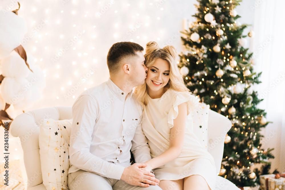 Portrait of a beautiful young family against the backdrop of the Christmas tree. Attractive family celebrates New year and smiles