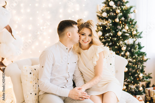 Portrait of a beautiful young family against the backdrop of the Christmas tree. Attractive family celebrates New year and smiles © ksyusha_yanovich
