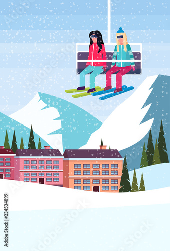 women couple skiers on chairlift ski resort hotel houses buildings winter snowy mountains landscape flat vertical