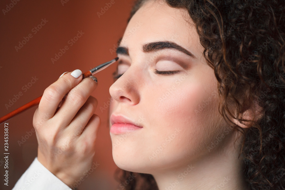 Closeup portrait of beautiful woman getting professional make-up with brush. Beauty and makeup concept