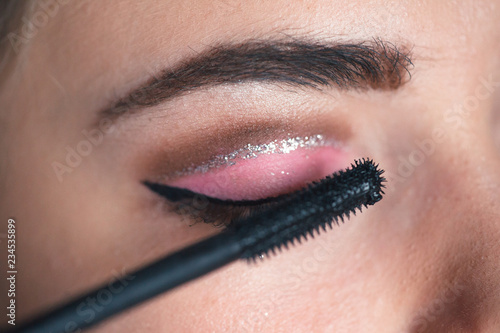 Closeup of makeup artist applying smokey eyes makeup. Eyelash extension procedure.