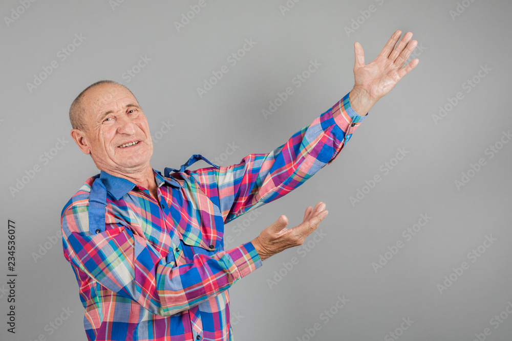 The elderly person point away. Serious Mature man pointing finger to the side, on grey background, copy space The elderly person point away. Serious Mature man pointing finger to the side, on grey background, copy space